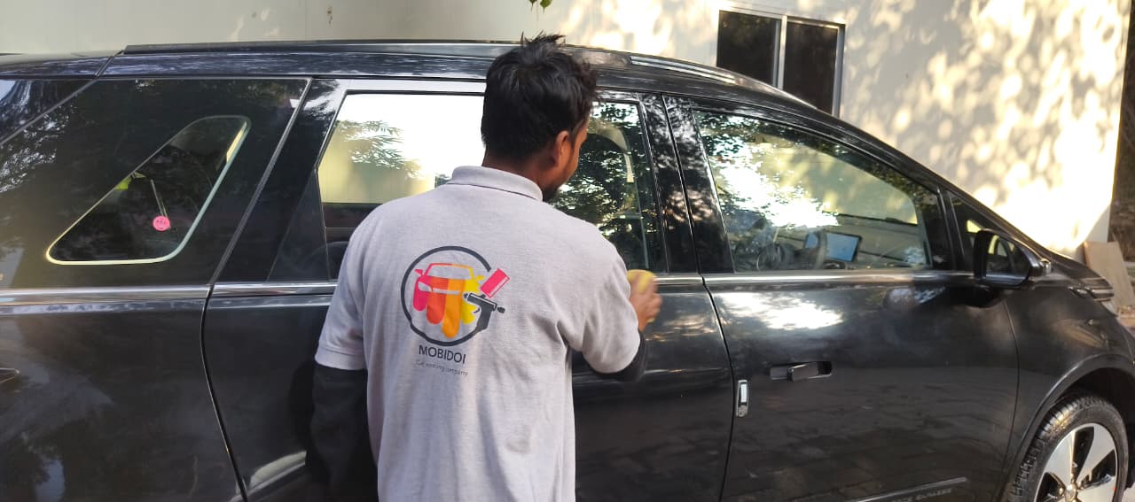 Mobidoi team member cleaning a black SUV