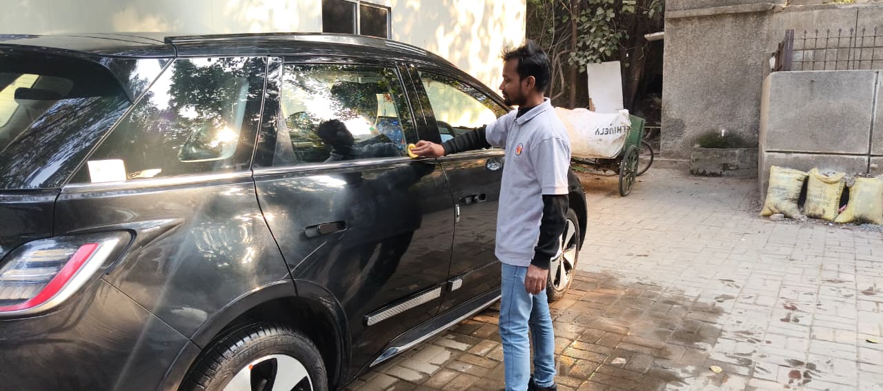 Mobidoi cleaner wiping an SUV's windows in a driveway